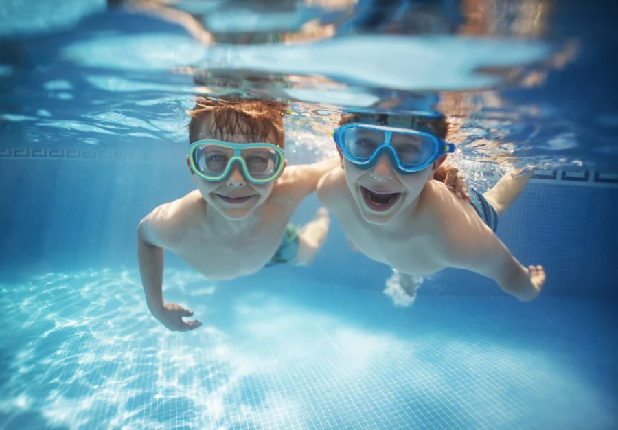 Zwei Kinder mit Taucherbrillen unter Wasser in einem Schwimmbad