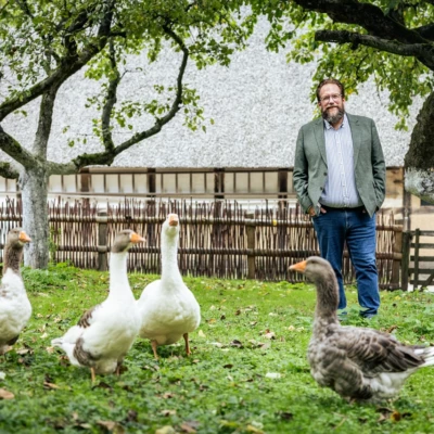 Stefan Zimmermann auf einer Wiese, vor ihm eine Gruppe Gänse