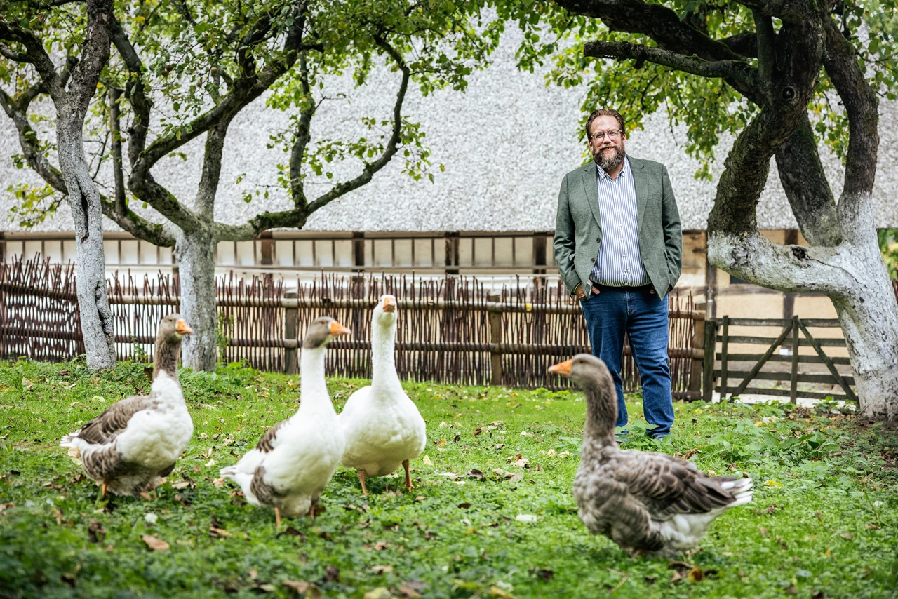 Stefan Zimmermann auf einer Wiese, vor ihm eine Gruppe Gänse